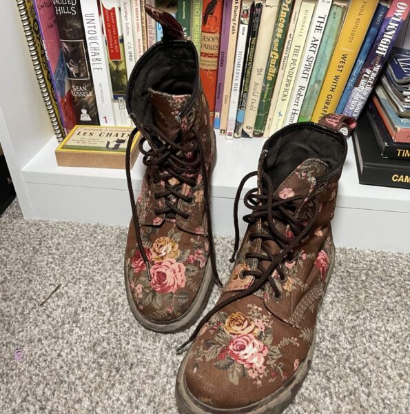 Doc Martin boots in floral pattern next to bookshelf